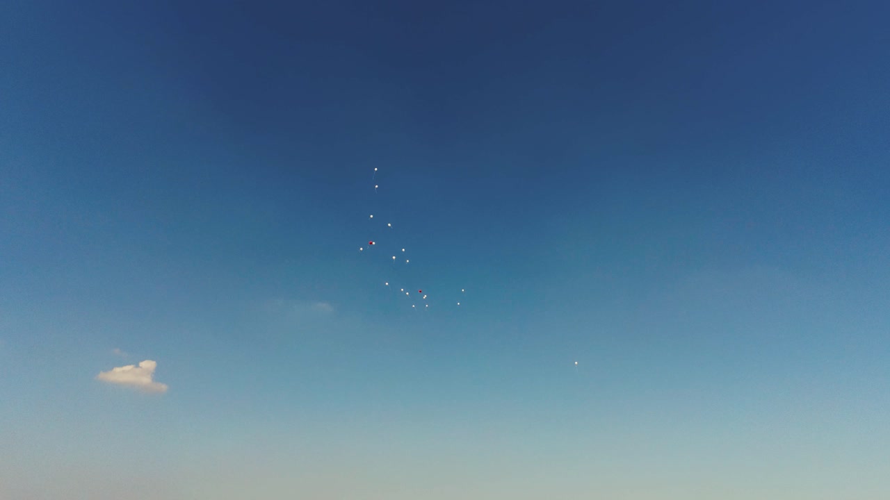 푸른 하늘에 잠복하는 일부 빨간색과 흰색 baloons의 영화 드론 샷