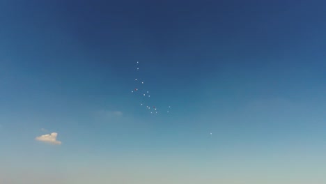 Una-Toma-Cinematográfica-De-Algunos-Globos-Rojos-Y-Blancos-Deslizándose-En-El-Cielo-Azul