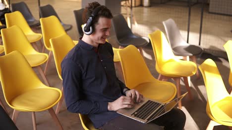 Un-Joven-Atractivo-Baila-Con-Música-En-Sus-Auriculares-Mientras-Trabaja-En-Una-Laptop