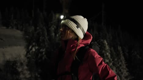 beautiful young woman camper with a headlamp standing looking around in the forest