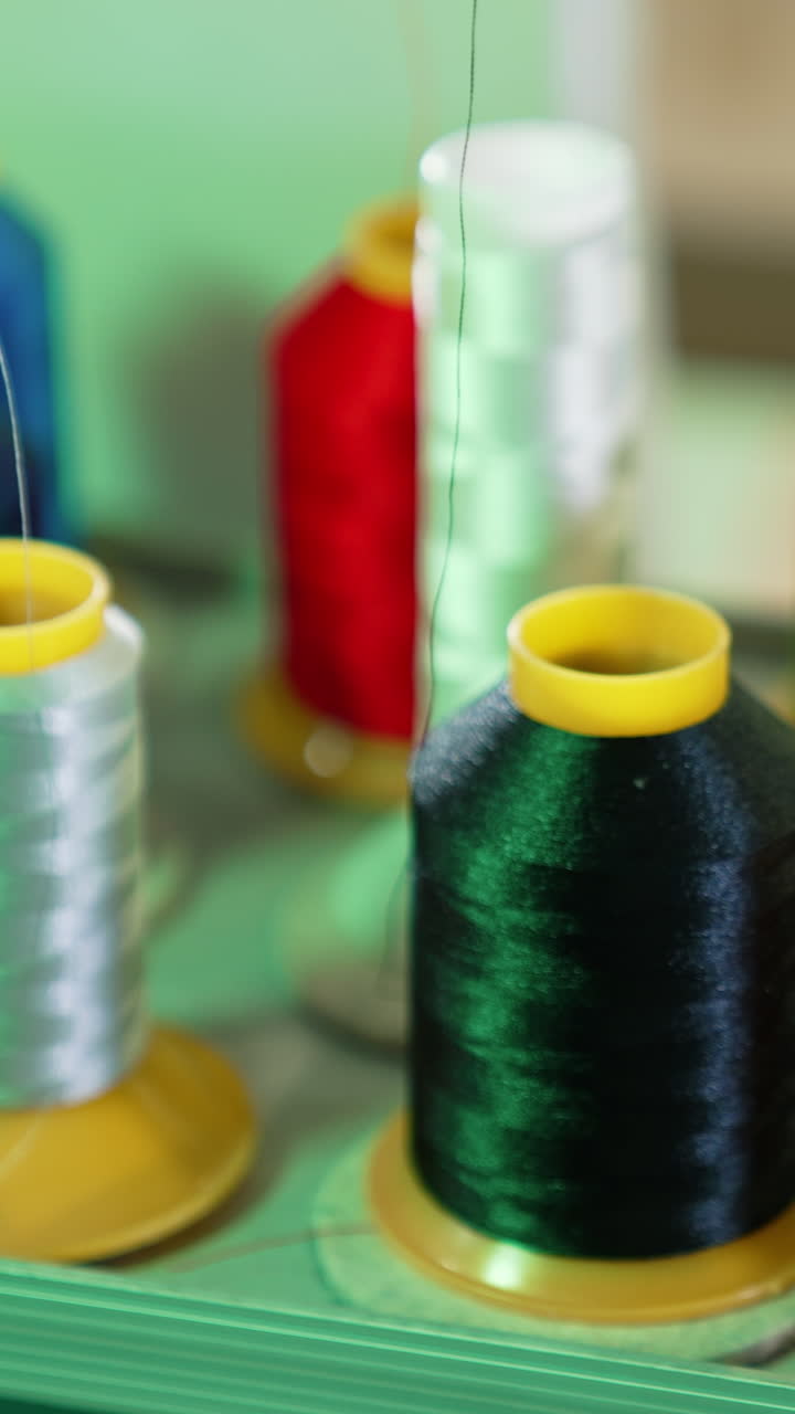 Bright threads in spools for tailor. Colorful spools with threads for sewing industry. Different colors of threads on the table. Handicraft. Vertical video