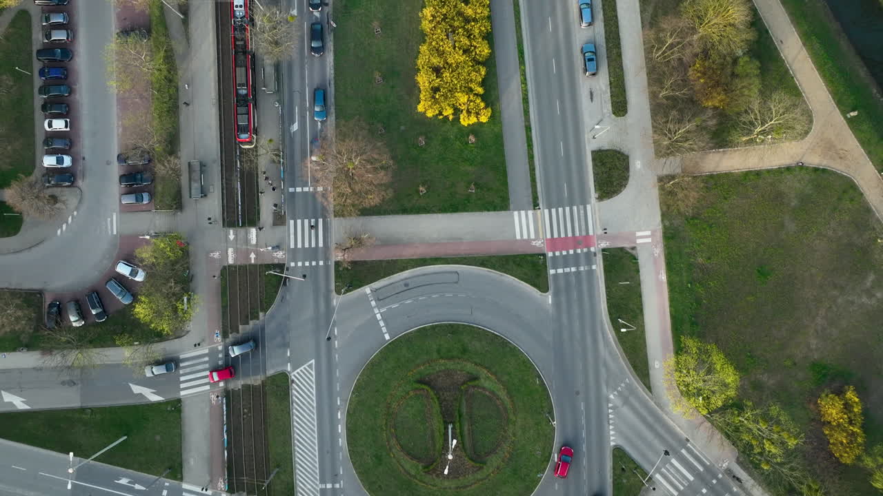 보행자 교차로와 초록색으로 둘러싸인 이동하는 차량과 함께 회전 교차로의 상공 전망