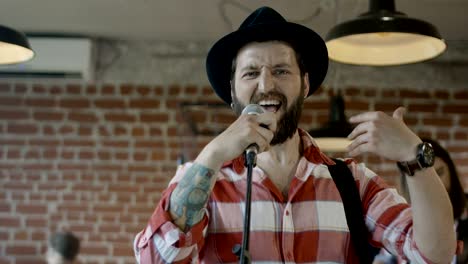 emotional bearded guitarist singing into microphone