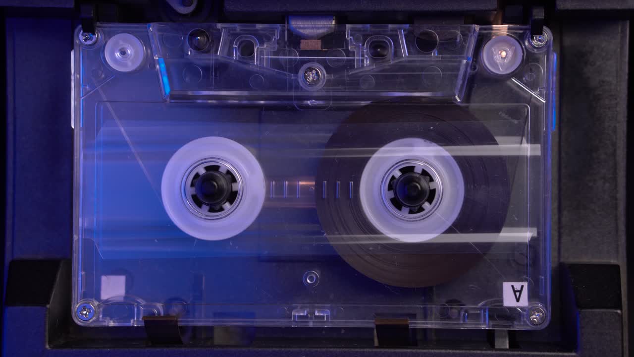 cinta de cassette de audio transparente que se reproduce desde el principio en el reproductor de cubiertas vintage, de cerca