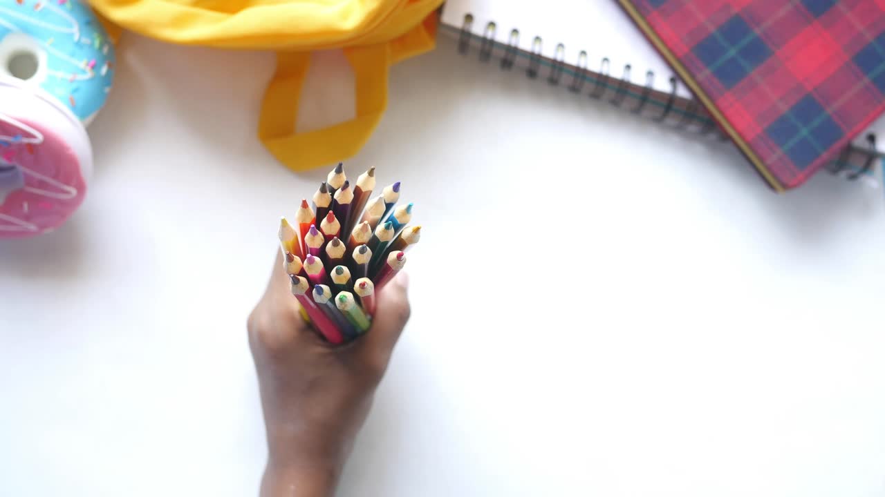 la mano del niño sosteniendo lápices de colores con suministros escolares
