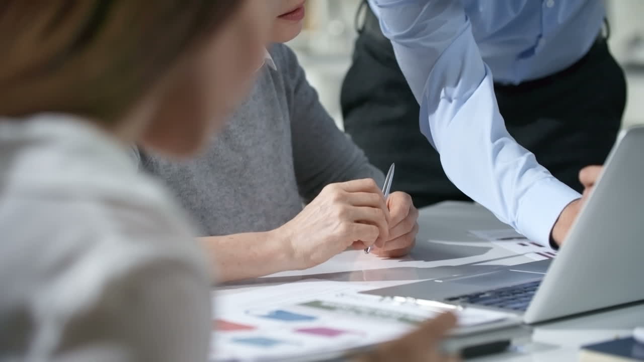 Two Coworkers Discuss A Project Looking At The Computer