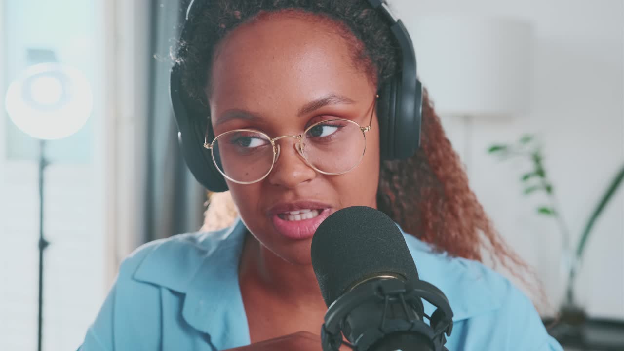Ung, afroamerikansk kvinde som radiovært med høretelefoner taler i mikrofonen