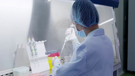 female scientist or researcher a lab coat use suction pipette dispensing purple liquid into 96 wells plate at modern laboratory cleanroom environmental facility setting