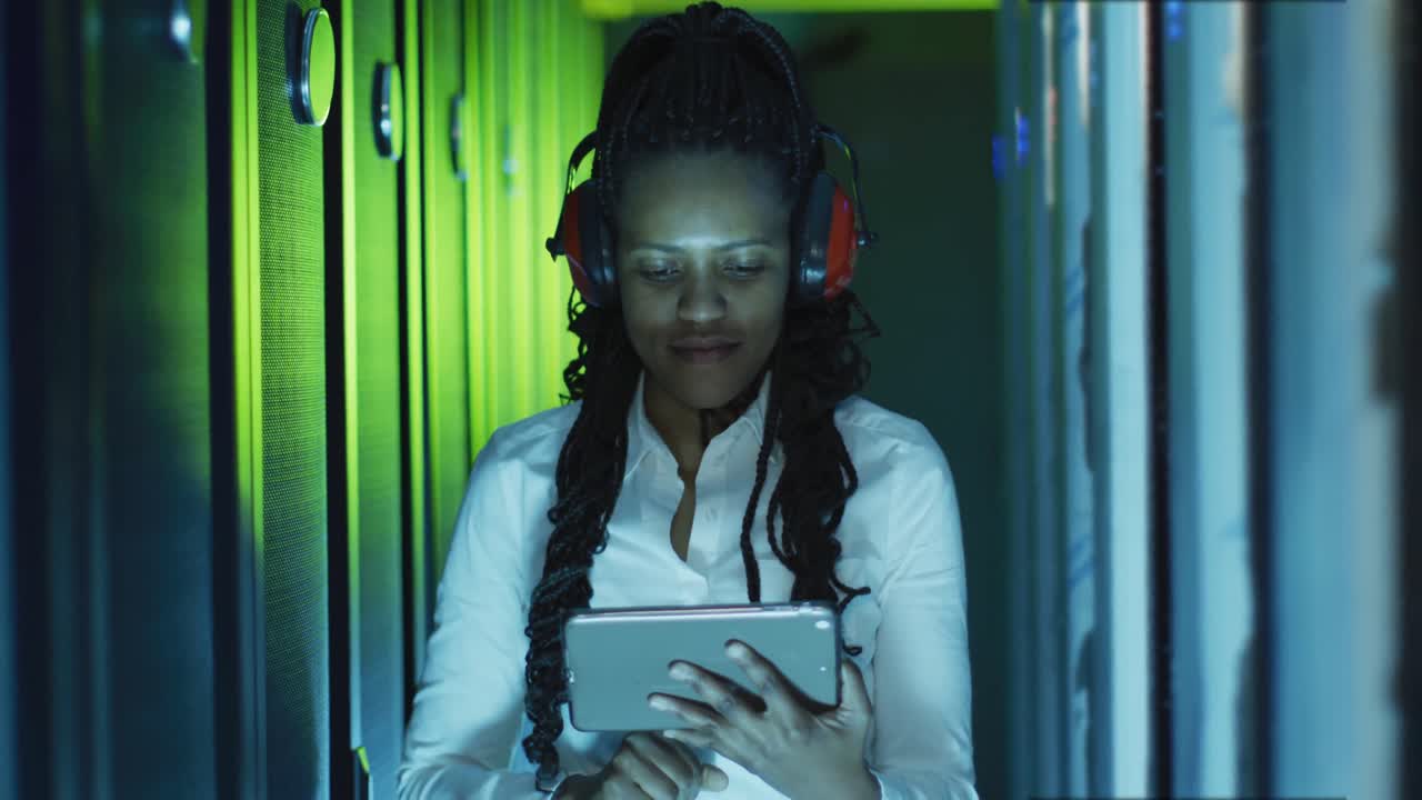 African american female computer technician using tablet working in business server room