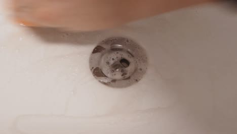 deep bathroom cleaning, hands washing shower drain hole, top-down, static