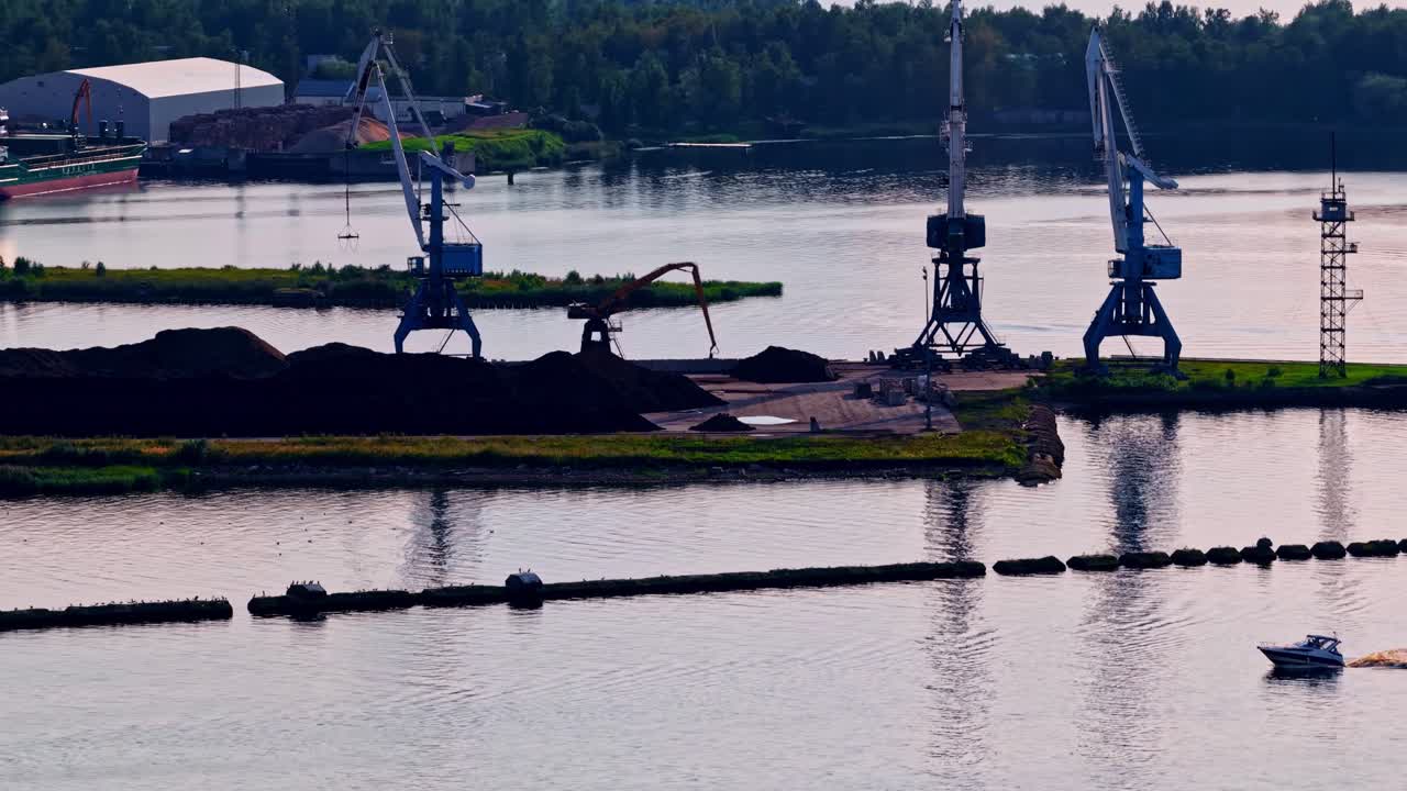 Industrial cranes by the river loading cargo under a clear sky