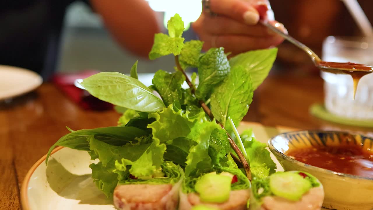 A vibrant Vietnamese dish is garnished with sauce in a Bangkok restaurant, highlighting fresh ingredients and culinary artistry