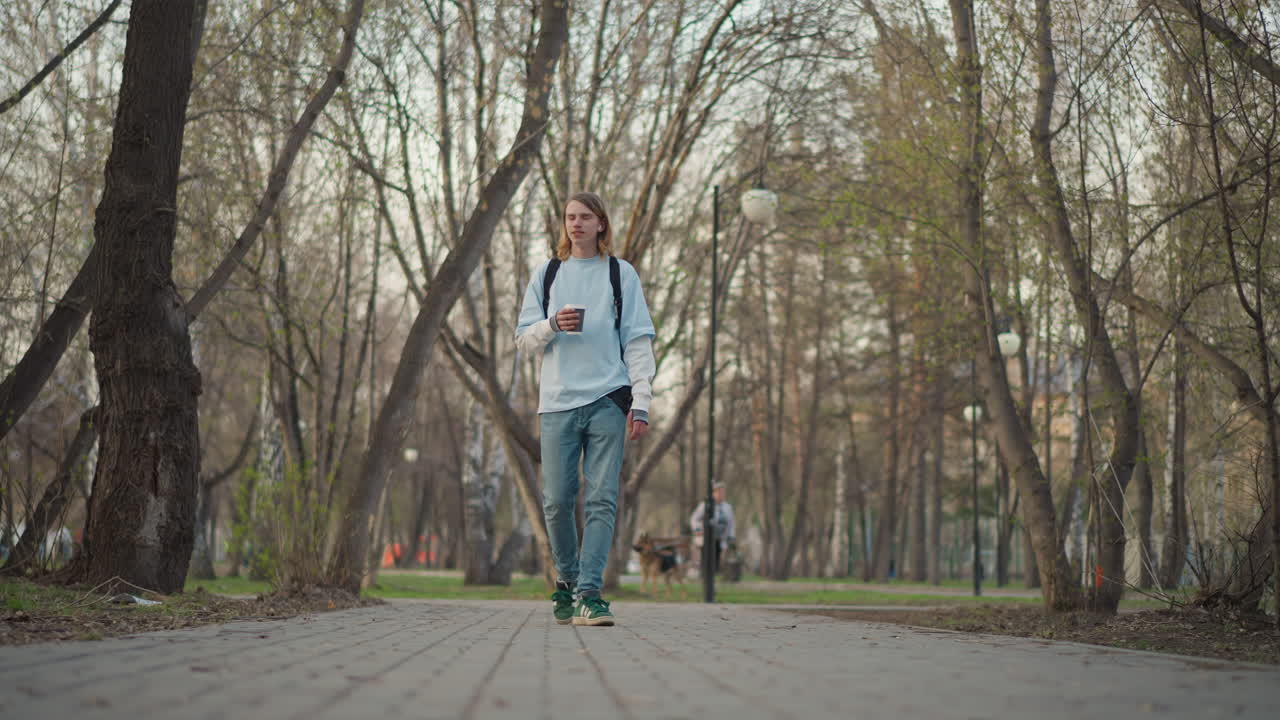 Un individuo tranquilo recorre un sendero boscoso, una persona pacífica deambula por una exuberante reserva natural arbolada, un hombre sereno camina por un sendero sombreado mientras bebe café y usa su teléfono