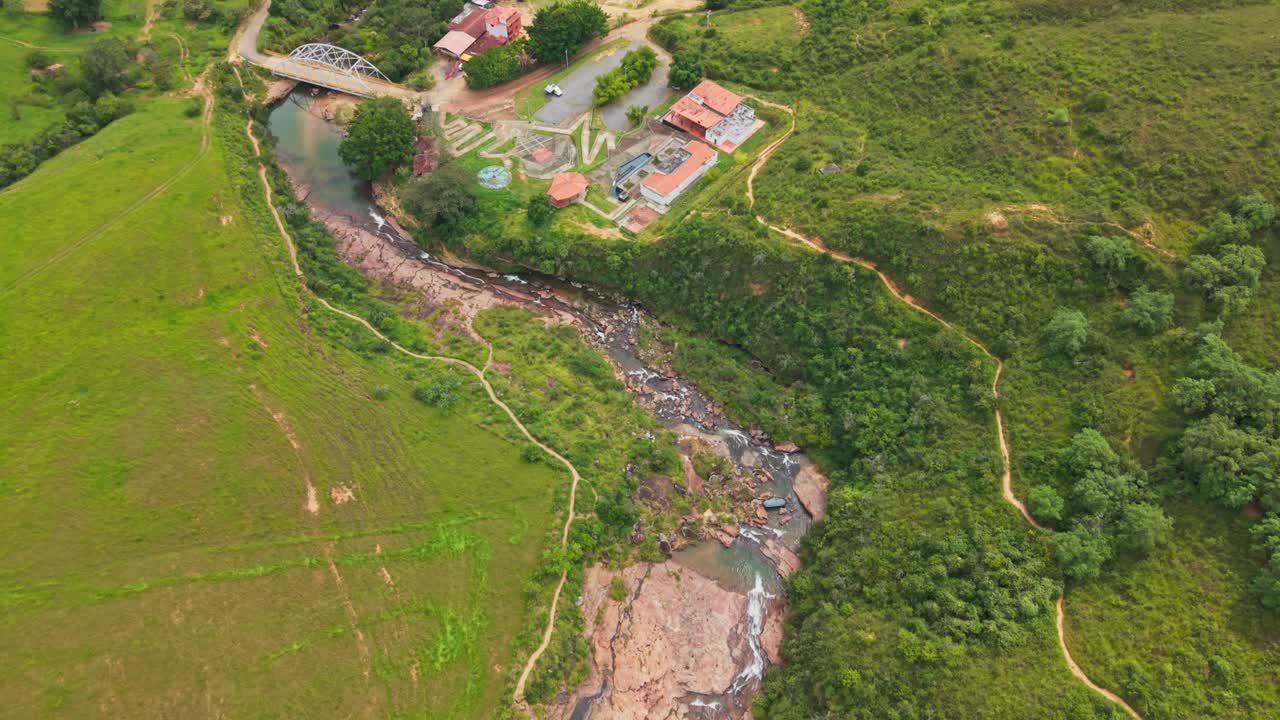 콜롬비아 산탄데르의 울창한 녹색 계곡에서 자연 풀이 있는 바위투성이 강 협곡을 따라가는 전방 항공 드론 샷