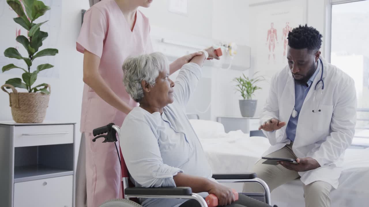 Diverse male doctor and female physio treating senior female patient in wheelchair, slow motion