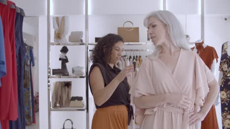 friendly shop assistant helping female customer in fitting room