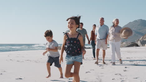 Familie-Mit-Mehreren-Generationen-Spaziert-Im-Sommerurlaub-Am-Sandstrand-Entlang