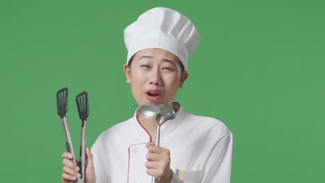 close up of asian woman chef holding ladle and singing while standing in the green screen background studio