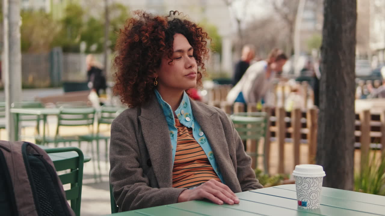 Young Woman Sits at Outdoor Cafe in the City