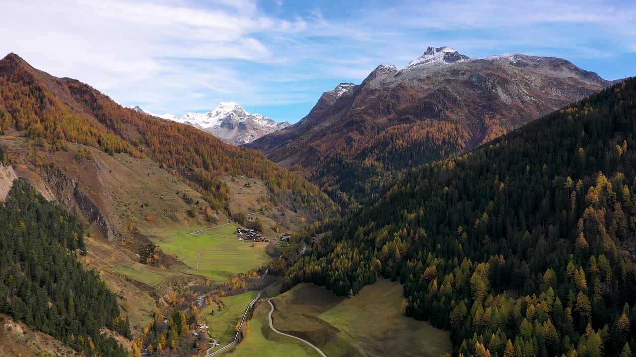 tiro de drone de pueblo suizo en otoño: otoño con montañas y un río en el fondo