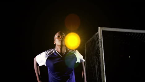 standing near goalpost, soccer player in blue jersey under bright stadium lights