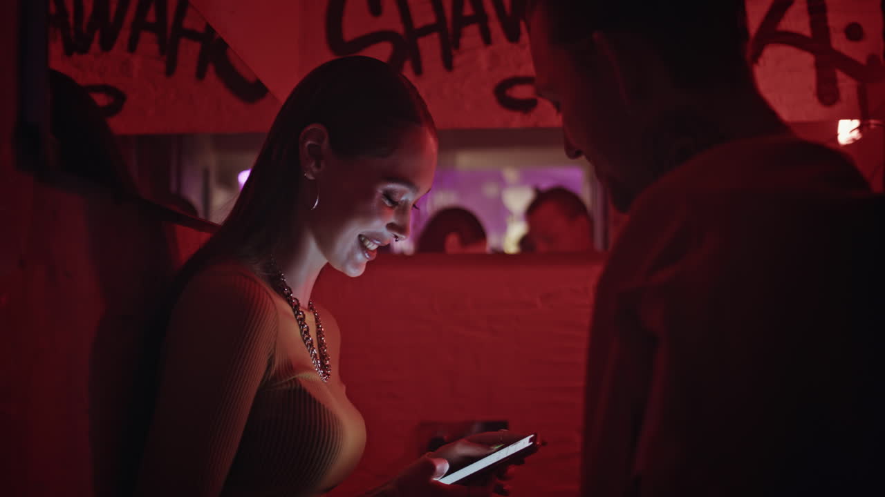 Dating woman holding mobile phone talking with boyfriend in red light closeup