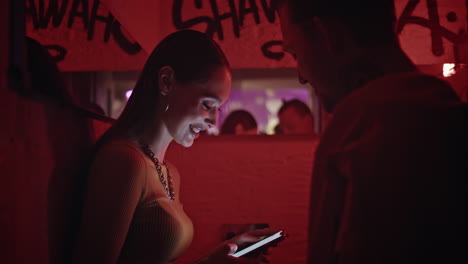 dating woman holding mobile phone talking with boyfriend in red light closeup