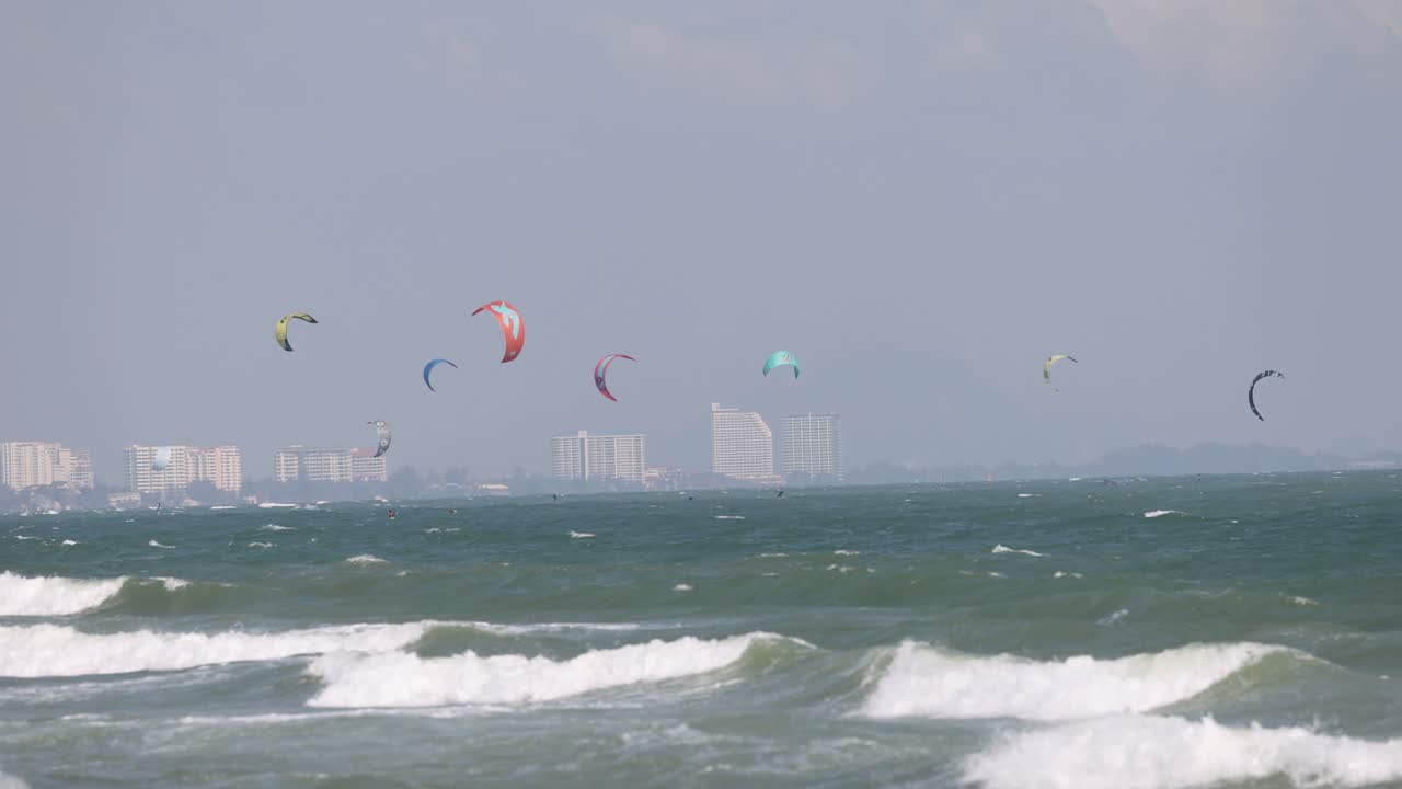 카이트 서퍼 들 은 도시 스카이 라인 근처 의 파도 위 에 미끄러진다