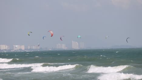 kite surfers glide over waves near city skyline