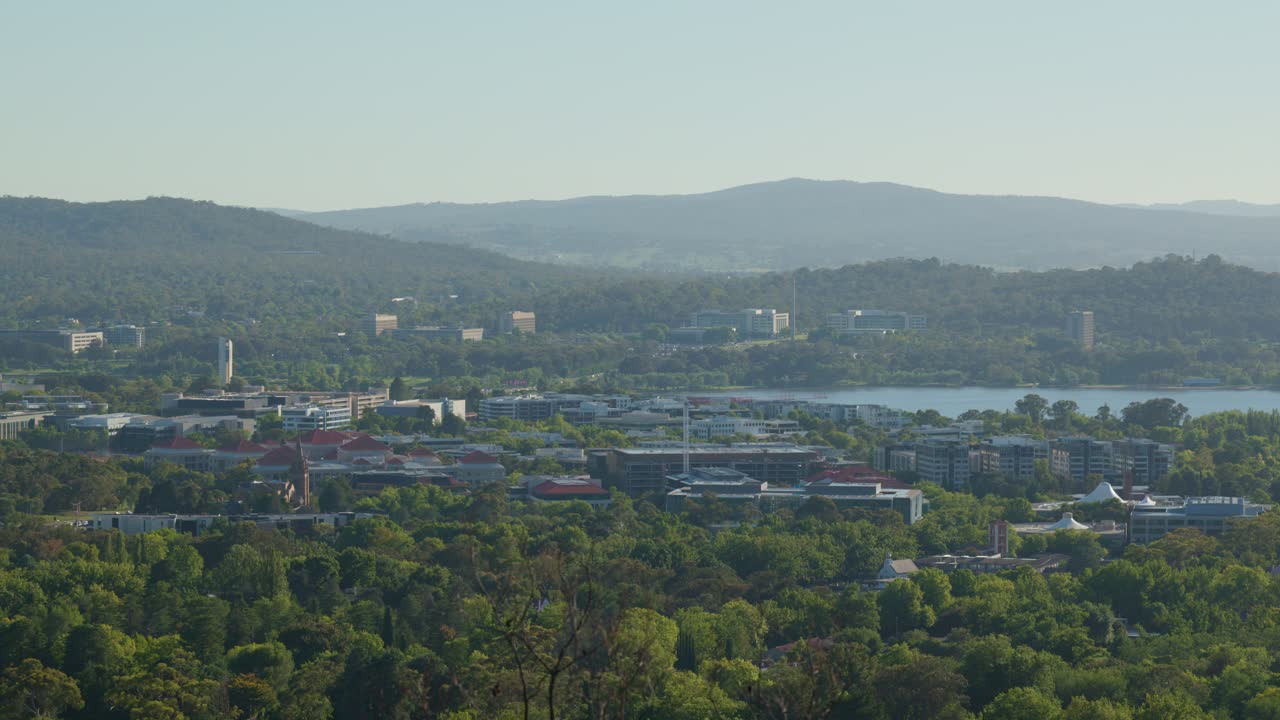 A morning view of the government office buildings in Barton, showcasing the commercial and administrative hub of Australia’s capital, framed by trees from Red Hill Lookout.