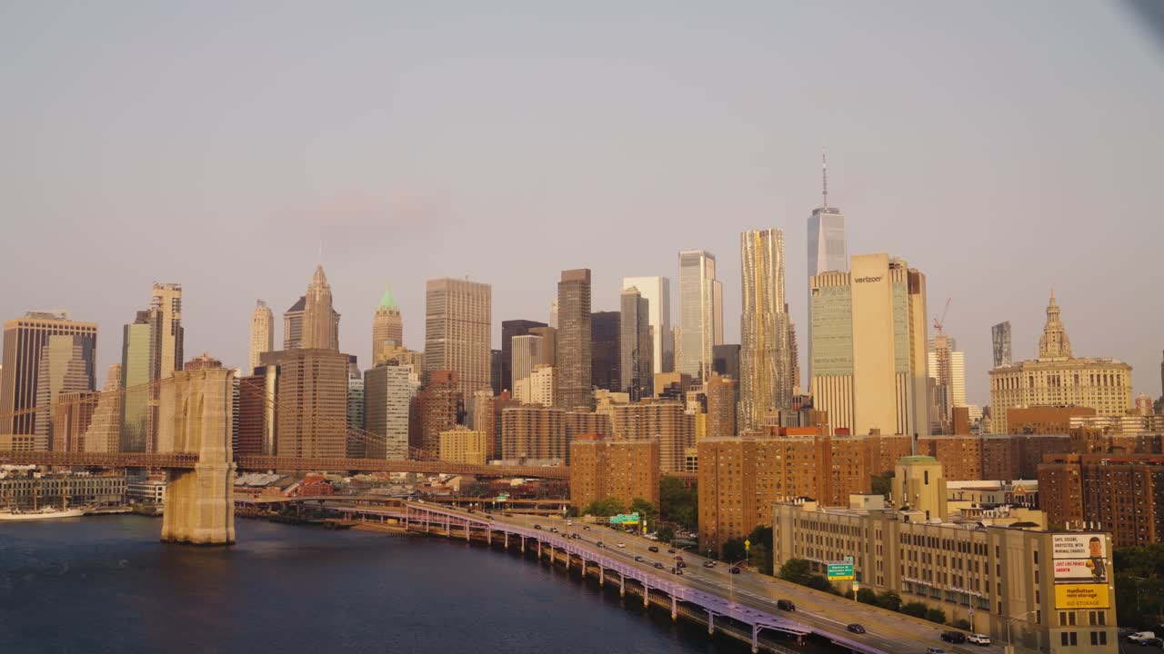 Pov dolly showing stunning skyline of New York City lighting by golden sun at sunset - Movement through fence of bridge - Panorama wide shot