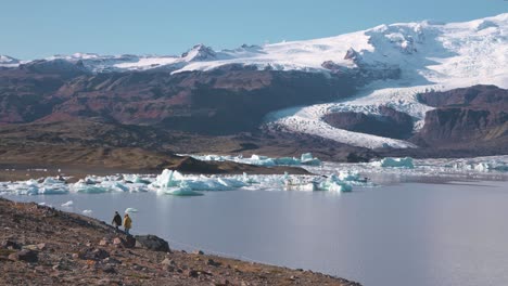 people walking along icy arctic fjallsárlón glacier lake in iceland