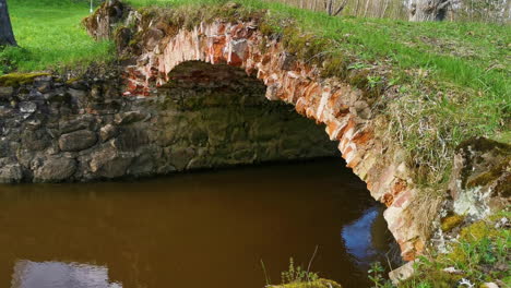 historic brick arch bridge over a gently flowing river surrounded by natural greenery