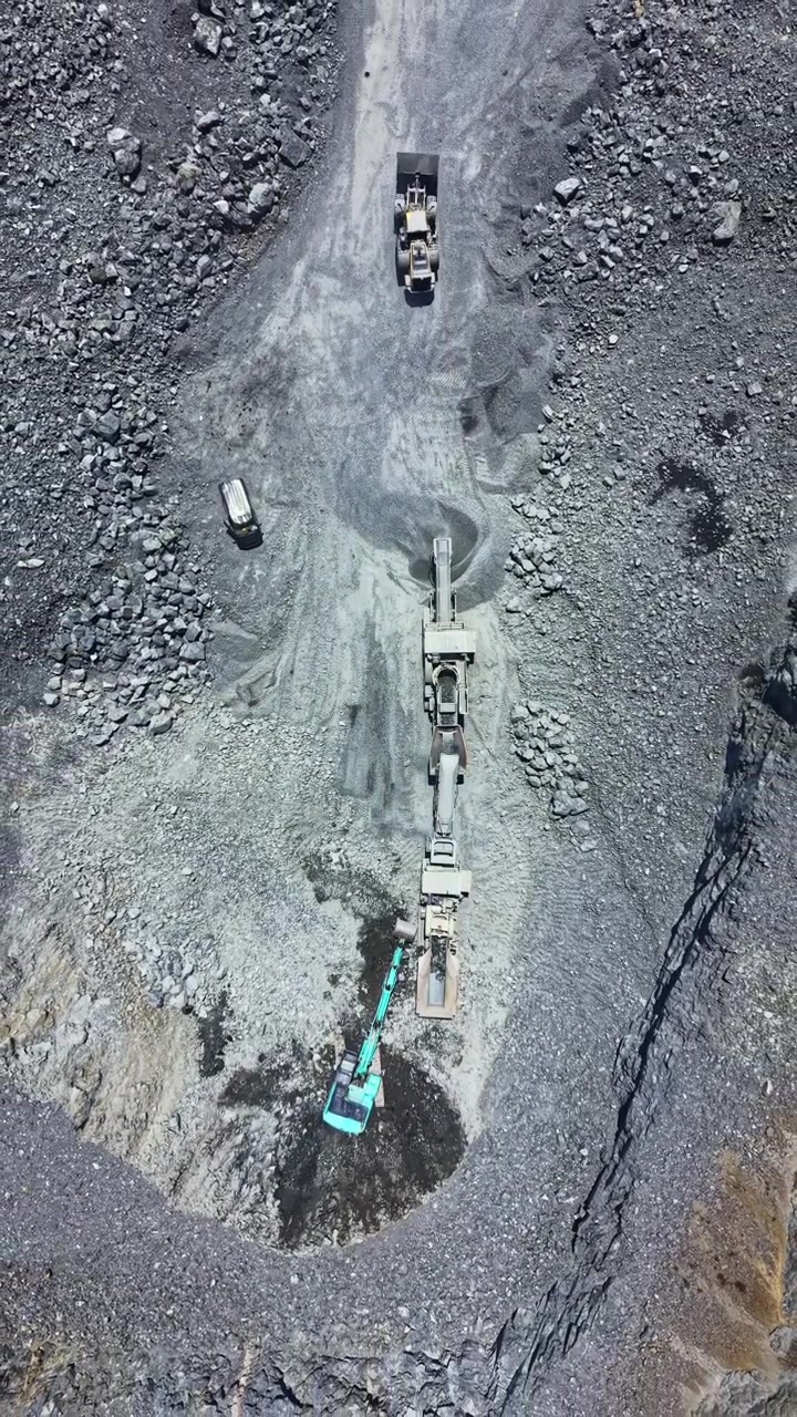 Granite quarry operation with machinery and trucks in action at a work site, displaying ongoing extraction and processing of stone materials