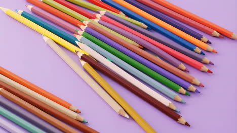 colorful pencils scattered on a purple background