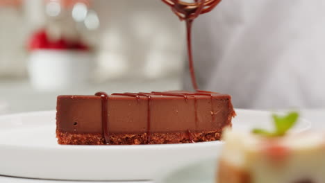 chef drizzling chocolate sauce over a cheesecake slice