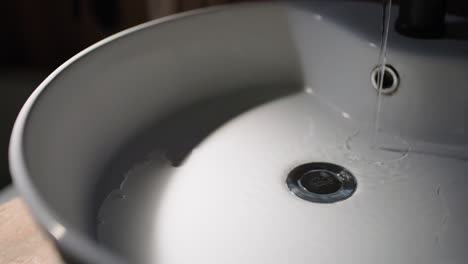 moody shoot of water running into an empty sink.