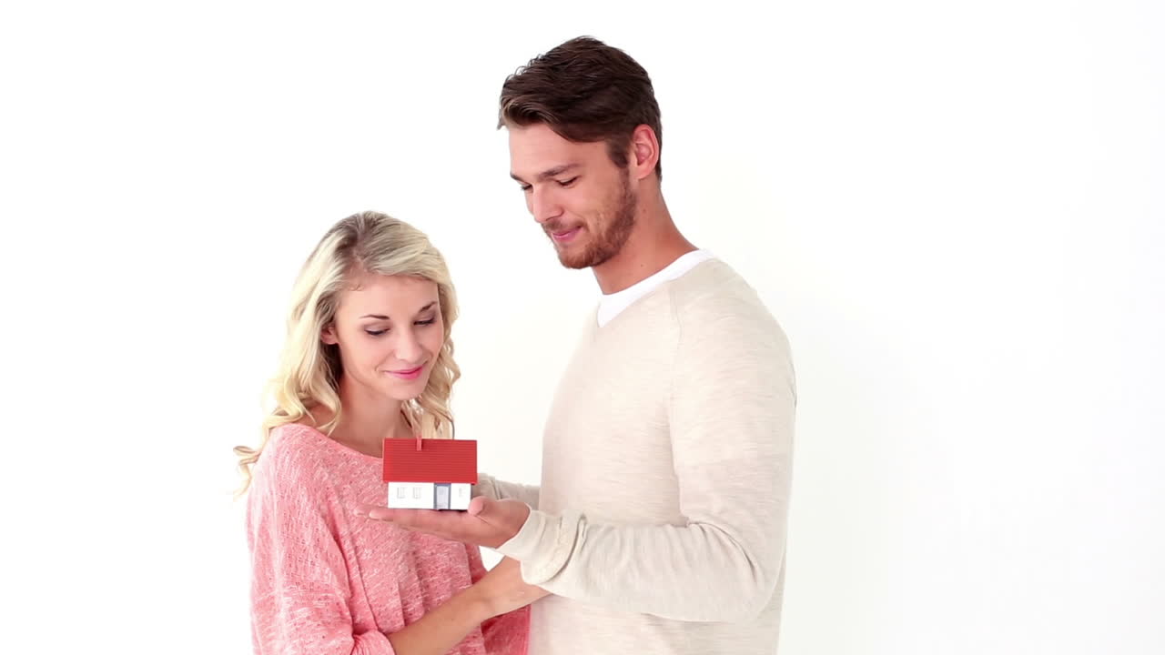 una pareja joven y atractiva con una mini casa.