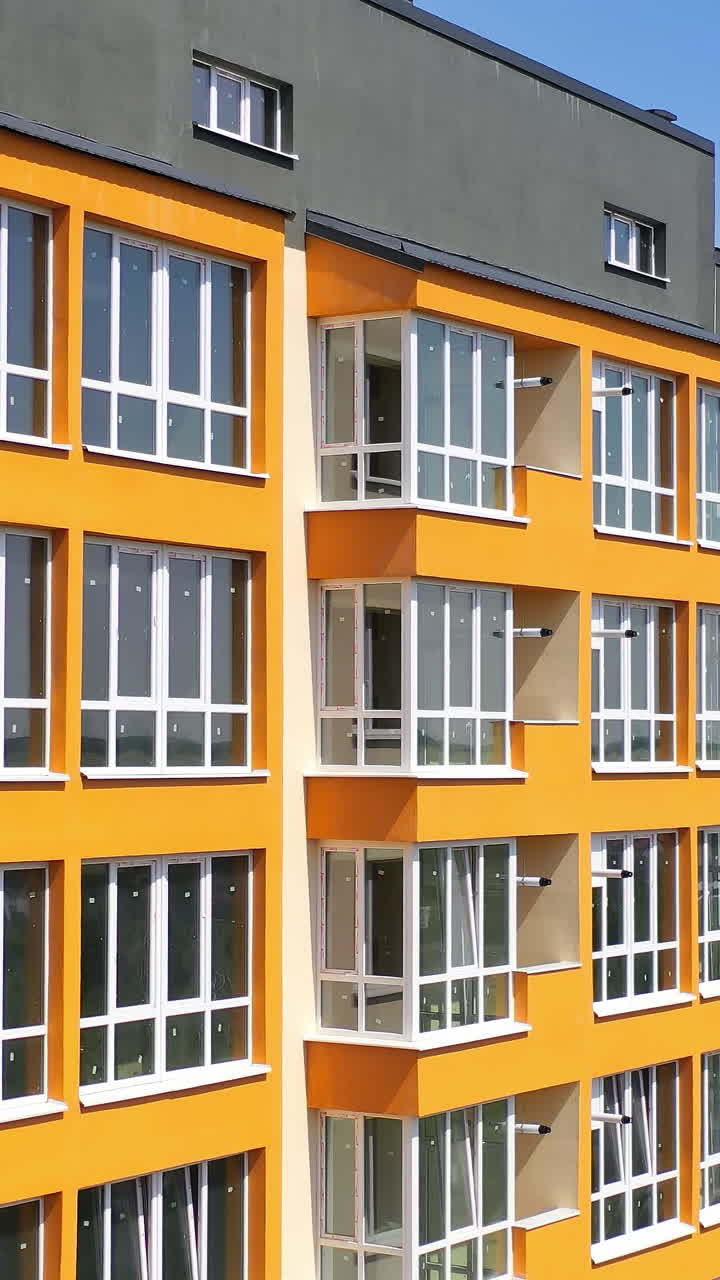 New multi storey in the city. Modern design of apartment building with orange walls with large balconies. Facade of luxury house for city residents. Vertical video