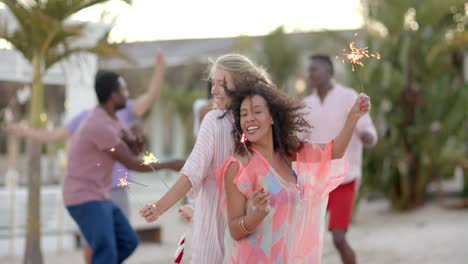 Feliz-Grupo-Diverso-De-Amigos-Bailando-Con-Bengalas-En-La-Playa