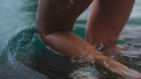 Close-up-of-caucasian-female-toned-legs-walking-into-pool,-slow-motion