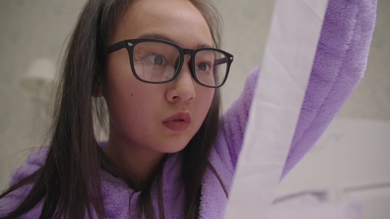 cerca de una mujer asiática de 20 años molesta con gafas mirando el recibo de una tienda grande.