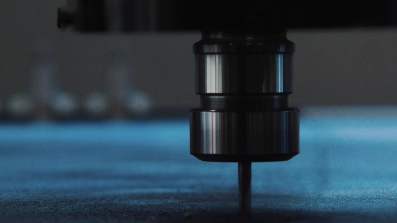 Macro frontale ravvicinata di una punta CNC sospesa sopra una tavola prima dell'inizio del processo di taglio.