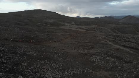 Imágenes-Espectaculares-De-Drones-Revelan-A-Cientos-De-Personas-Caminando-Al-Unísono-En-Una-Ladera-De-Montaña-Vasta-Y-Escarpada,-Destacando-La-Grandeza-De-La-Exploración-Comunitaria.