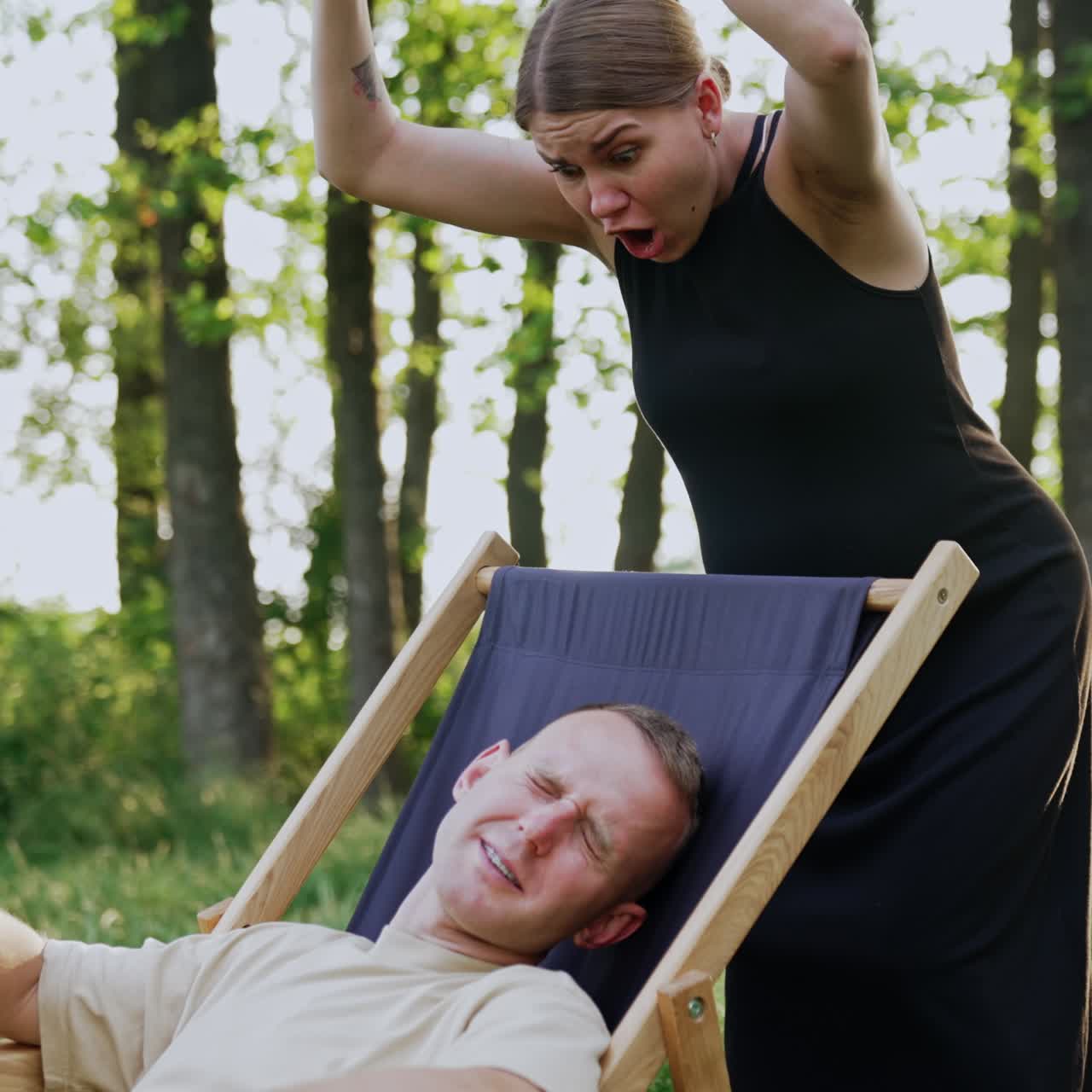 Man working remotely in the nature took a break for a nap. Pregnant wife tells him off for laziness