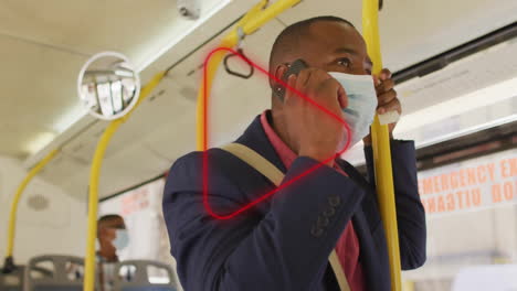 standing in public bus, man wearing mask talking on phone