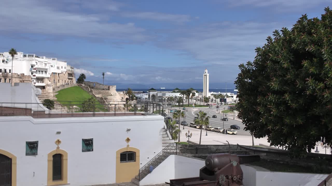 Wide establishing pan right over white walls and traditional Islamic architecture to Masjid Lalla Abosh in the distance, Tangier, Morocco