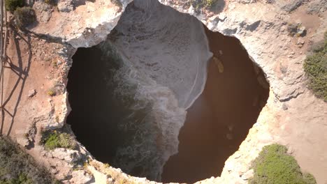 Drohnenansicht-Von-Oben-Nach-Unten-Auf-Meereswellen,-Die-In-Der-Meereshöhle-Von-Benagil-Zusammenbrechen