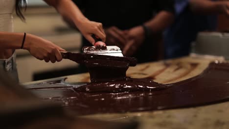 girl tempering chocolate making process with spatula on granite counter