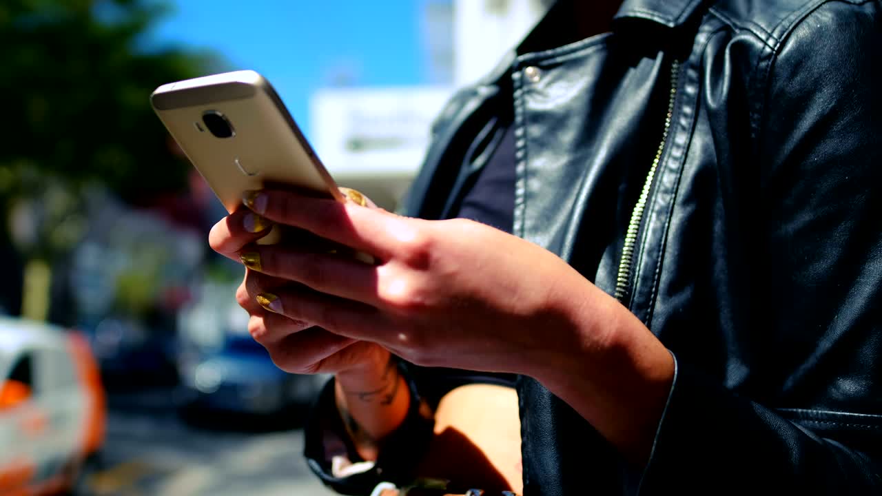 mujer de cabello rosa usando teléfono móvil en el callejón 4k